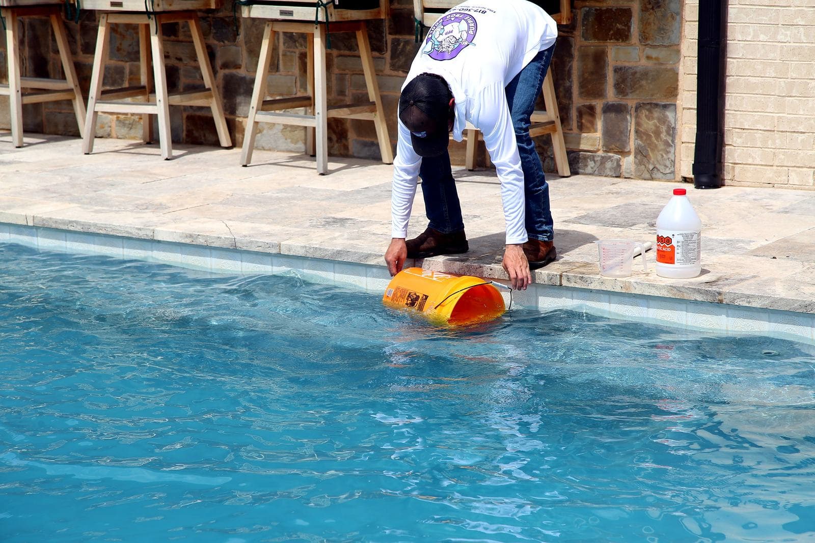 Purple Frog Pools technician balancing water chemistry at the edge of a residential pool